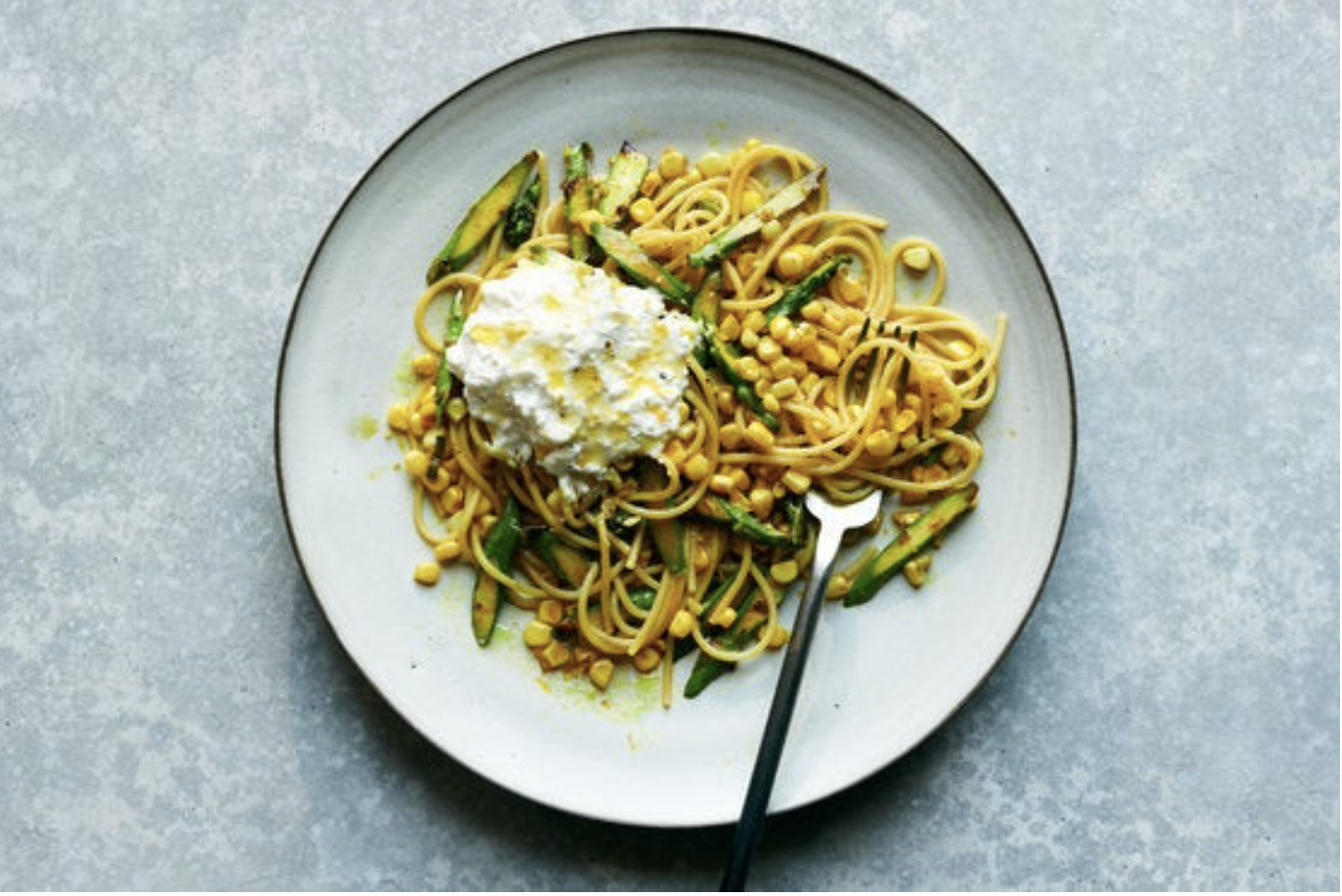 Caramelized corn and asparagus pasta with ricotta cheese in a serving dish